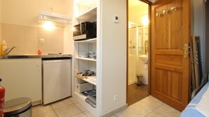 A compact kitchen with a refrigerator, microwave, and sink. There's a wooden door leading to a bathroom. - Studio with sea view, parking, and pets allowed in La Hague (La Hague)