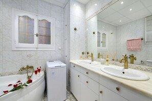 Une salle de bain avec deux lavabos, une baignoire et un grand miroir.