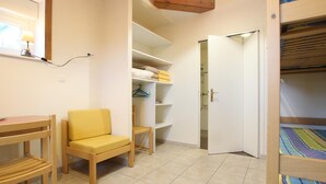 A compact room with a bed, a chair, a small table, and a wardrobe with shelves. - Unique studio in La Hague, PMR access, pets allowed and WiFi (La Hague)