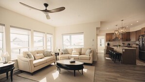 A spacious living room with a large sofa, a coffee table, and a ceiling fan. - Brand New Ski in/out + Hot Tub!. (Big White)