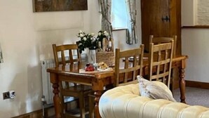 A room with a wooden dining table, four chairs, a cream-colored sofa, and a painting on the wall. - The Bell Tower, Orchardleigh Estate (Frome)