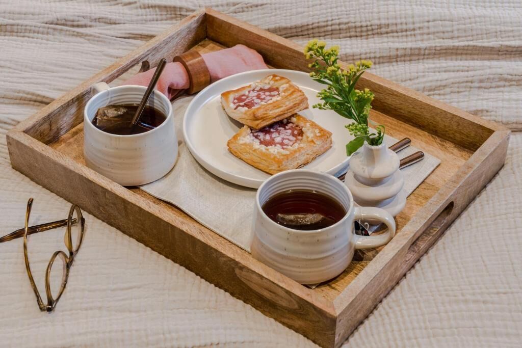 A tray with pastries, a cup of tea, and a small vase with flowers.
