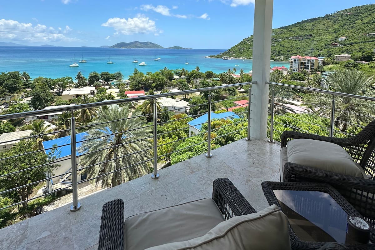 Un espacio de estar techado al aire libre con vista al mar y una ladera.