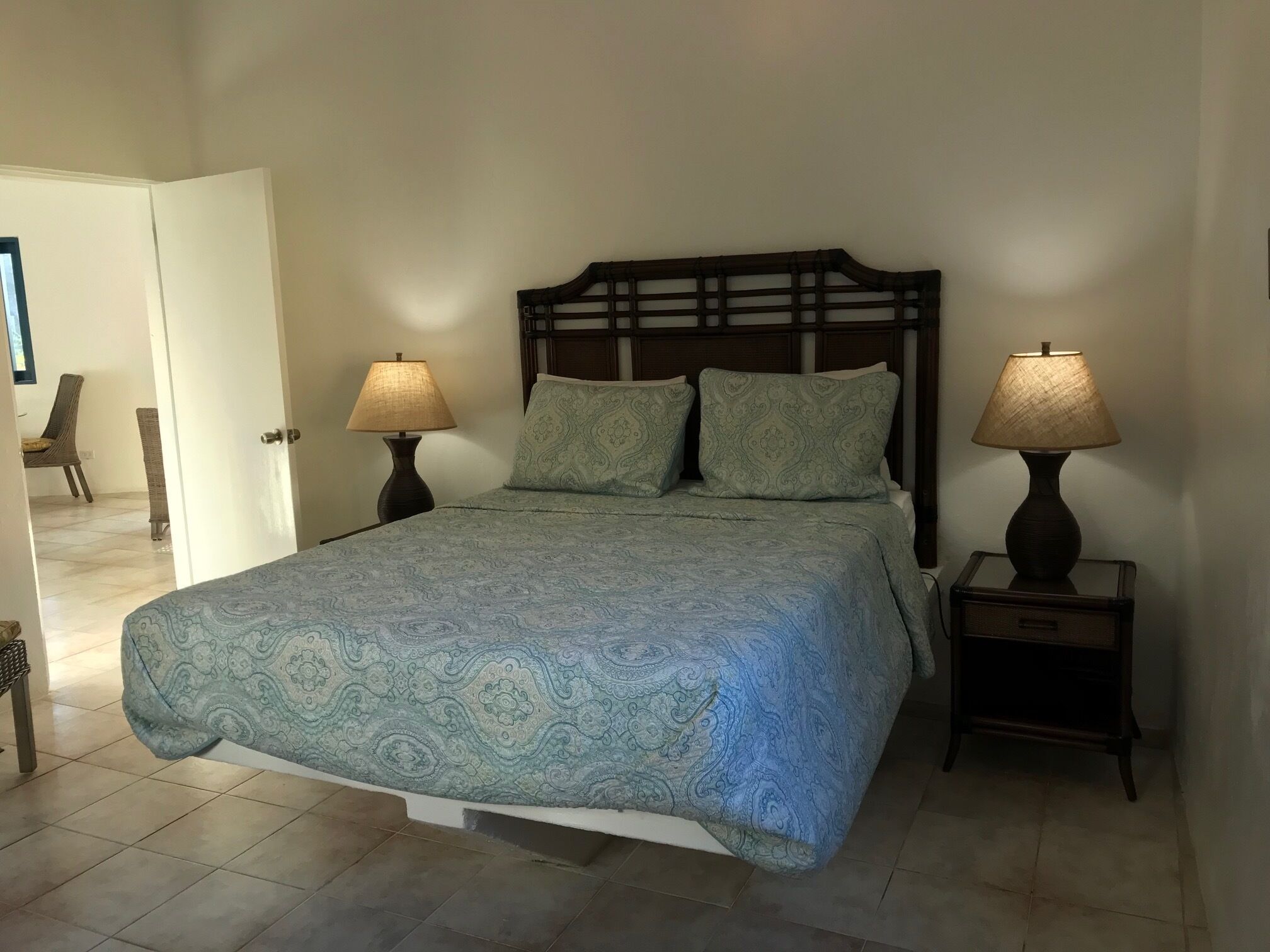 A bedroom with a bed, two bedside tables, and two lamps.