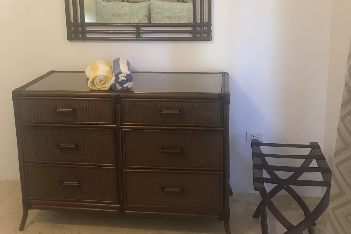 Un aparador de madera oscura con varios cajones y un espejo encima.