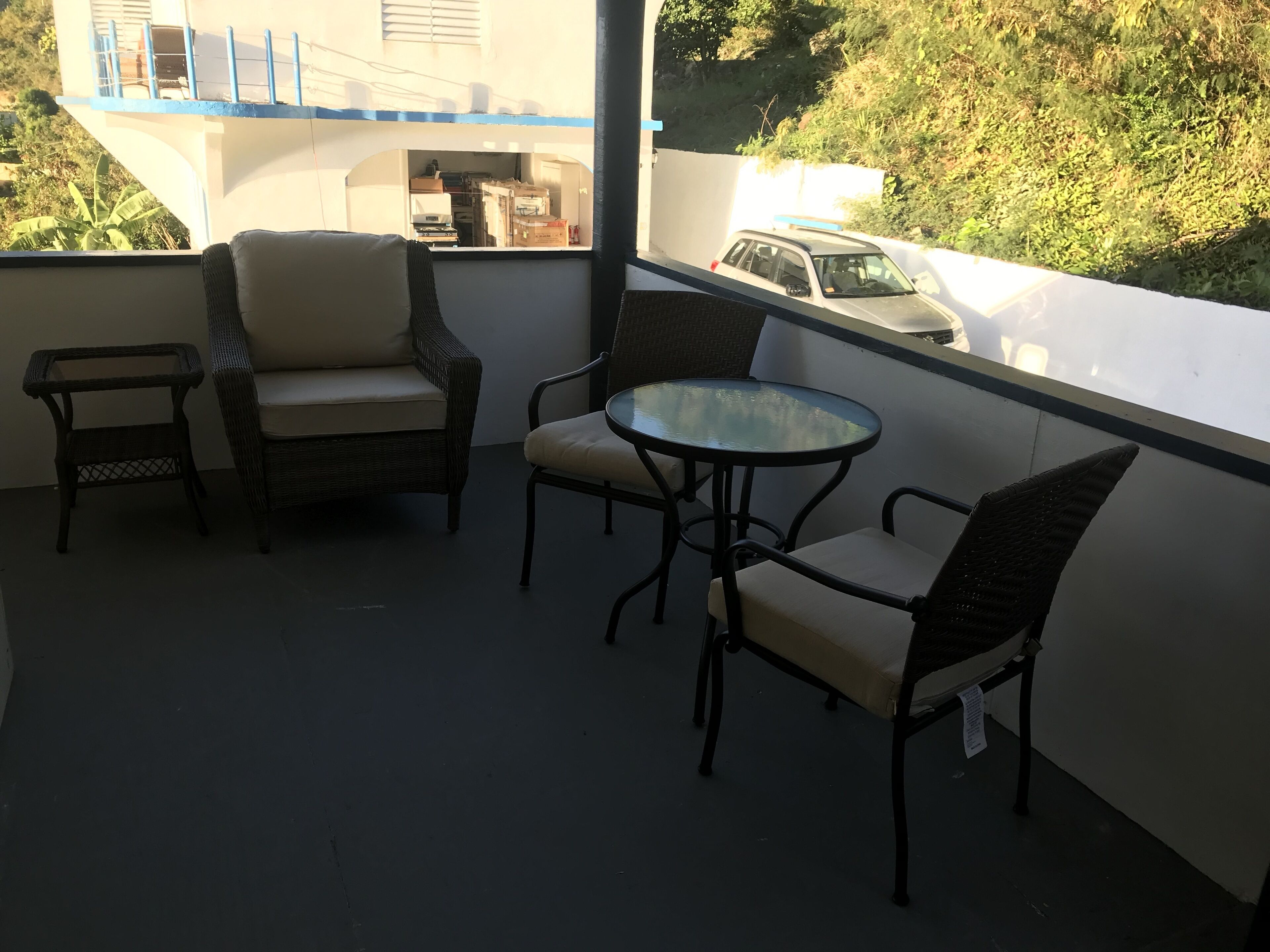Un balcon agrémenté de meubles en osier et d’une table en verre.