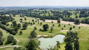 Un parcours de golf comportant plusieurs trous, un étang et des zones boisées environnantes.