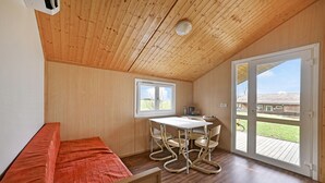 A room with a wooden ceiling, a dining table with chairs, a bench, and a sliding glass door leading outside. - Lovely home in Barjac with outdoor swimming pool (Barjac)