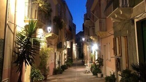 Une ruelle étroite, bordée de bâtiments des deux côtés, éclairée par des lampadaires.