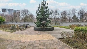 A park with a central tree, benches, and a paved walkway. - Spacious Apartment | Two Bedrooms and Terrace (Gdańsk)
