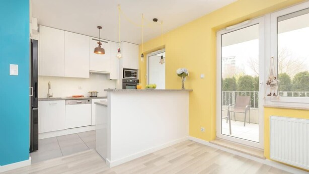 A modern kitchen with white cabinets, a central island, and pendant lighting. - Spacious Apartment | Two Bedrooms and Terrace (Gdańsk)