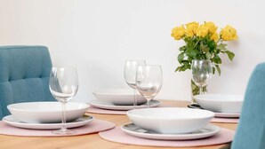 A dining table with white plates, pink placemats, and clear wine glasses. - Spacious Apartment | Two Bedrooms and Terrace (Gdańsk)
