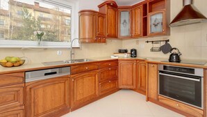 Une cuisine avec des meubles de rangement en bois, un lave-vaisselle, un four et une fenêtre donnant sur des immeubles.