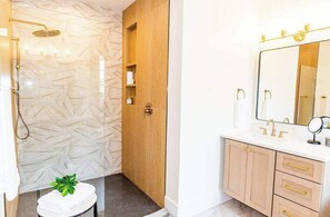 A bathroom with a shower, toilet, and vanity with a mirror.