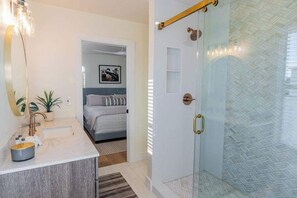 A bathroom with a sink, mirror, and shower.