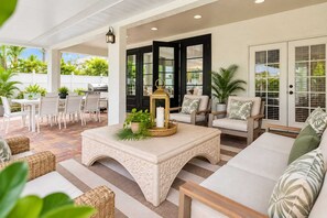 An outdoor patio area with a white table and chairs, a cushioned sofa, and a decorative lantern. - 10082 Paradise Palms Retreat (Naples)
