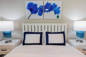 A hotel room with a bed, two bedside tables, a white headboard, and two wall-mounted paintings of blue flowers. - 5332 Aqua Haven - Waterfall Pool (Naples)