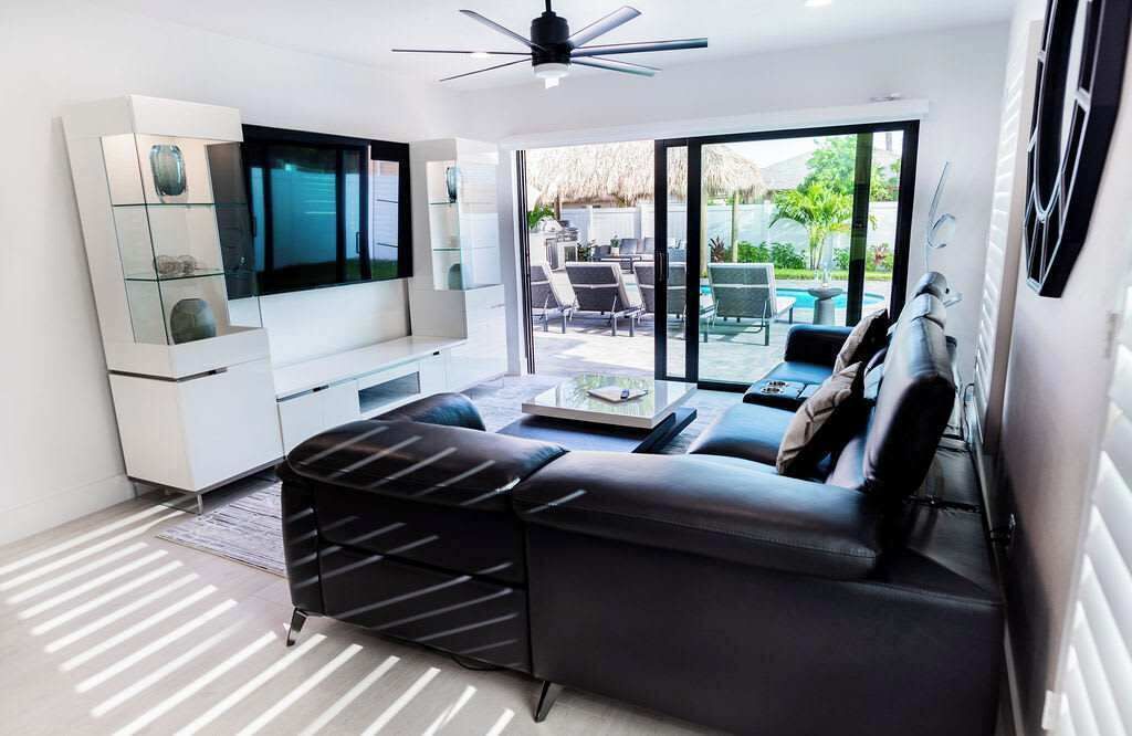 A modern living room with a sofa, TV, and a view of an outdoor patio.