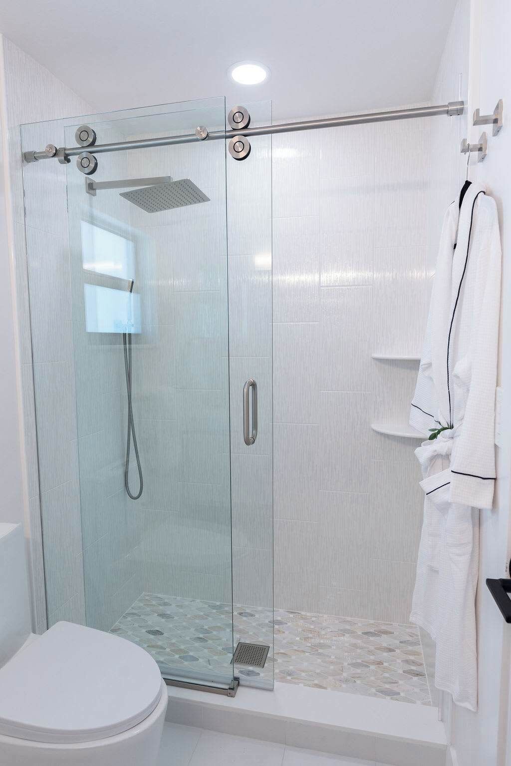Een moderne badkamer met een douchecabine van glas, een toilet en een handdoekhouder.