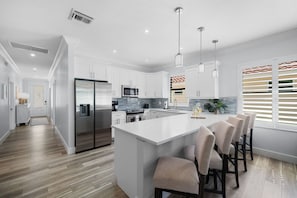 A modern kitchen with a large island, stainless steel appliances, and pendant lighting.