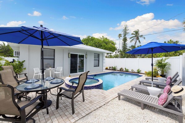 Un jardin avec une piscine, du mobilier d’extérieur et des parasols.