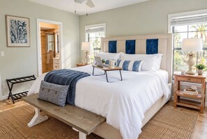 A bedroom with a large bed, bedside tables, a bench, and a window with a view.