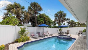 A swimming pool with a tiled edge, lounge chairs, and umbrellas. - 798 Barefoot Bungalow ·Heated Pool/Spa· Bike2Beach (Naples)