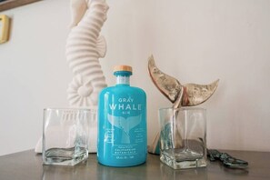 Une bouteille de gin Gray Whale et deux verres sur une table.