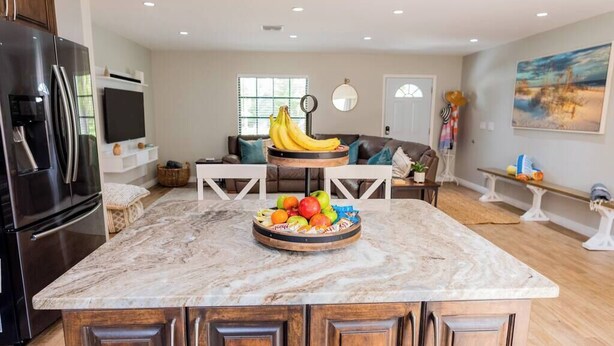 A kitchen with a marble countertop, a refrigerator, and a fruit bowl. - 798 Barefoot Bungalow ·Heated Pool/Spa· Bike2Beach (Naples)