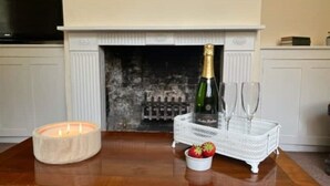 Una mesa de madera con una vela, una botella de champán, dos copas y una cesta con fresas.