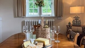 Una mesa de comedor con queso, copas de vino y una cesta de pan.