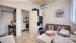 A modern kitchen with white cabinets, a black and white checkered backsplash, and a dining area with a table set for two. - Modern Apartment Sant Orsola by Wonderful Italy (Bologna)