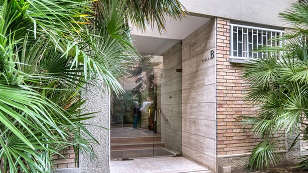 A modern building entrance with a glass door, a brick wall, and a staircase leading inside. - Modern Apartment Sant Orsola by Wonderful Italy (Bologna)