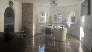 A dining area with a stone wall, a chandelier, and a view through a window. - 3 Zimmer Ferienwohnung, Schwarzwald, Nationalpark in der Nähe,haustierfreundlich (Baiersbronn)