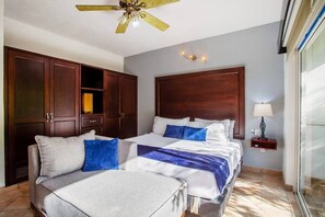 Relax in this stylish room with a large bed and two additional beds, a wardrobe, and a table with a lamp.