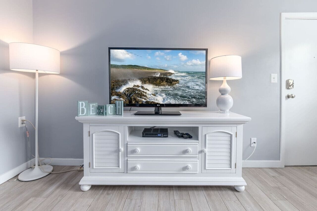 Eine weiße Unterhaltungseinrichtung mit einem Flachbildfernseher, einer Lampe und einigen dekorativen Gegenständen.