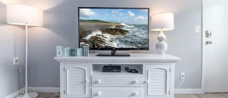 A white entertainment unit with a flat-screen TV, a lamp, and a few decorative items.