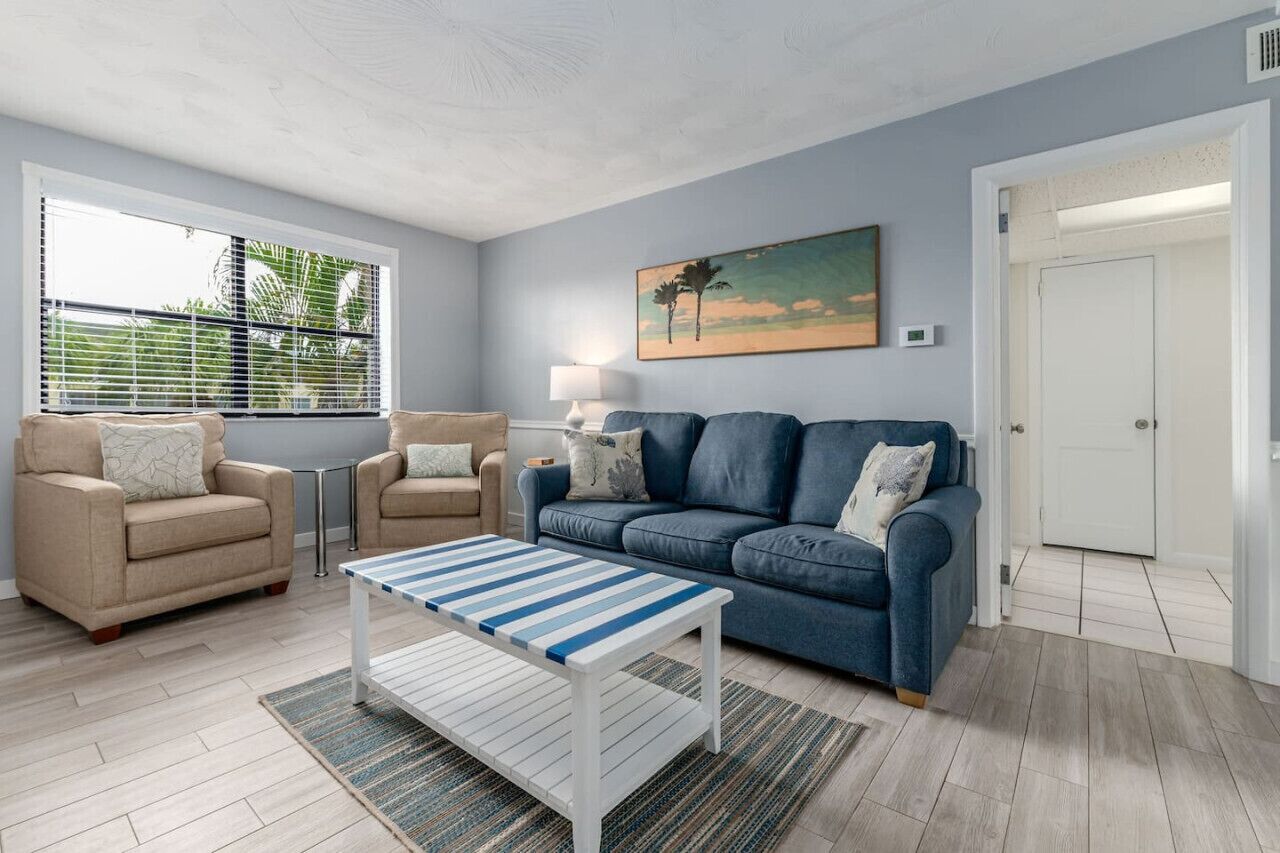 Una sala de estar con un sofá beige, un sofá azul y una mesa de centro a rayas.
