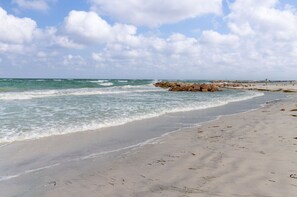 A beach with a rocky breakwater and calm waves. - Friendly Native Retreat: 2BD|1BR| Walk to Beach! (St. Pete Beach/Tierra Verde)