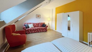 A cozy loft bedroom with a sloped ceiling, a red floral sofa, a white wardrobe, and a striped bed. - Big flat with fresh renovation,free parking,SonyPS (Duisburg)