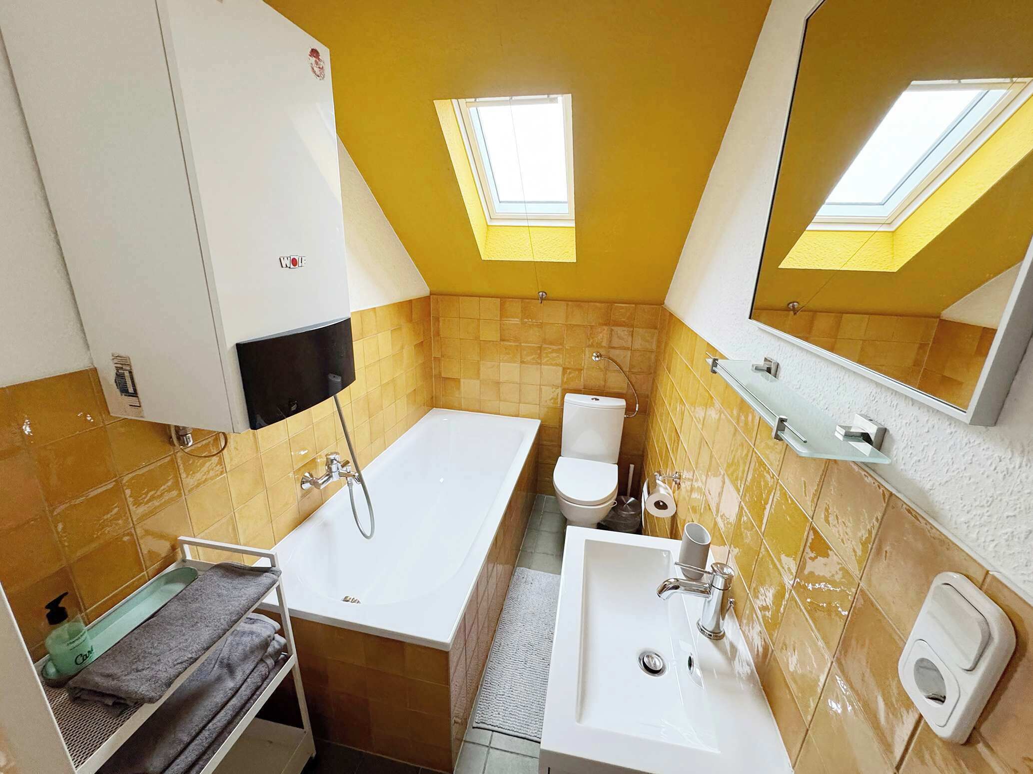 Un bagno con vasca, WC, lavandino e uno specchio. Si vedono asciugamani e articoli da toilette.
