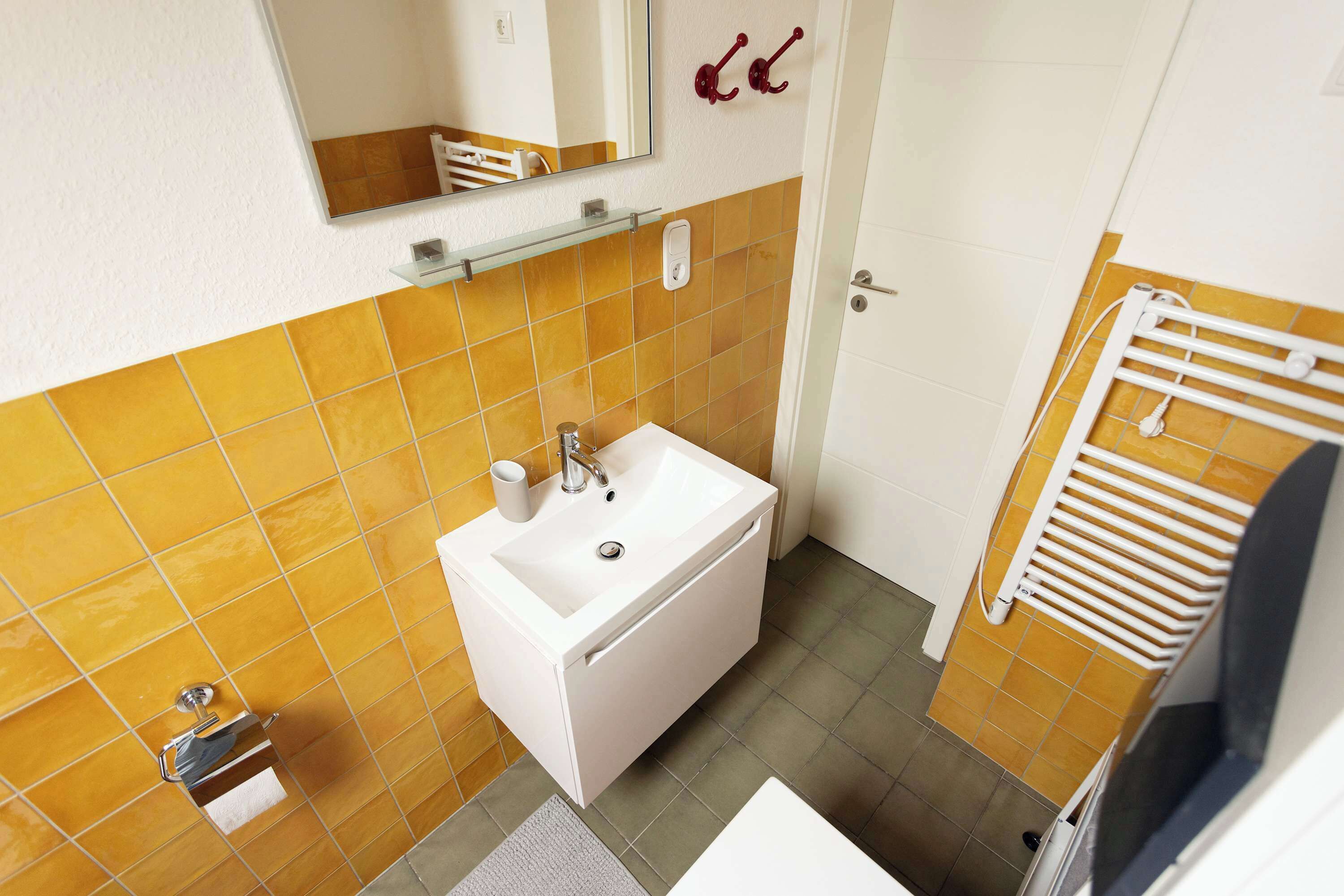 A bathroom with a white sink, a mirror, and a towel rack.