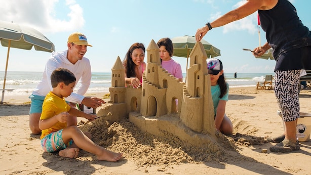 Eine Gruppe von Menschen baut eine Sandburg am Strand.