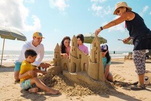 Eine Gruppe von Menschen baut eine Sandburg am Strand.