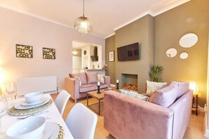 Een moderne woonkamer met een bank, salontafel en een eetgedeelte met wit servies.