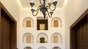 A hallway with a chandelier, wooden doors, and wall-mounted owl sculptures. - The Owl House (Chania)