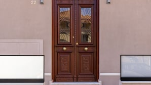 A double wooden door with glass panels, a small light fixture above, and a number '22' on the wall. - The Owl House (Chania)