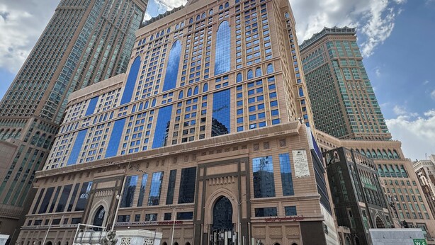 Un grand bâtiment historique, doté d’un imposant clocher et surplombé par plusieurs gratte-ciel.