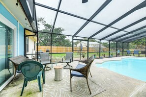 Área externa coberta com piscina, móveis de vime e vista para o quintal.