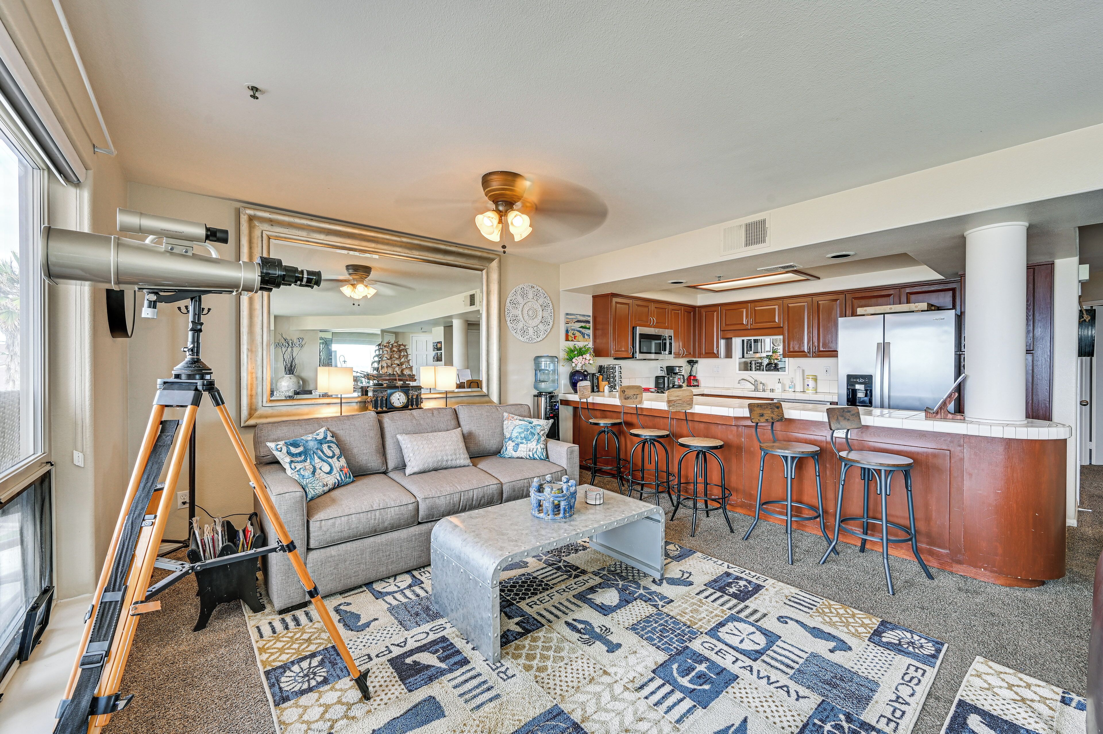 A modern kitchen with wooden cabinets, a stainless steel refrigerator, and a bar area with stools.